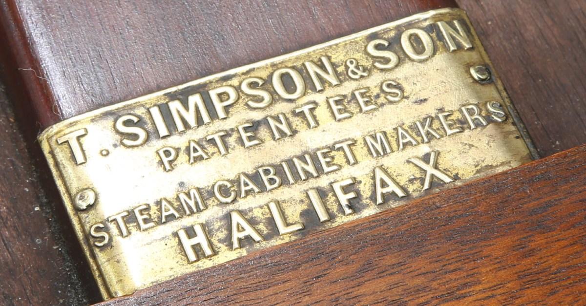 The brass maker's label showing the desk to have been made by T Simpson &amp; Son of Halifax.