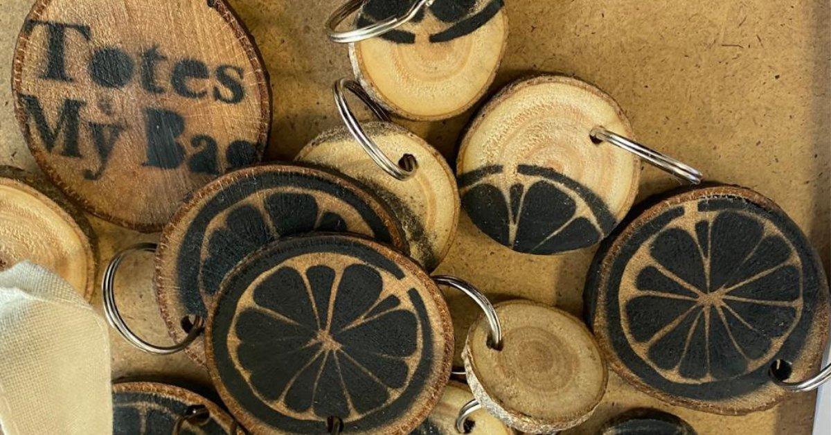 A pile of wooden keyrings showing the 'orange slice' logo of the students' company, Totes My Bag.