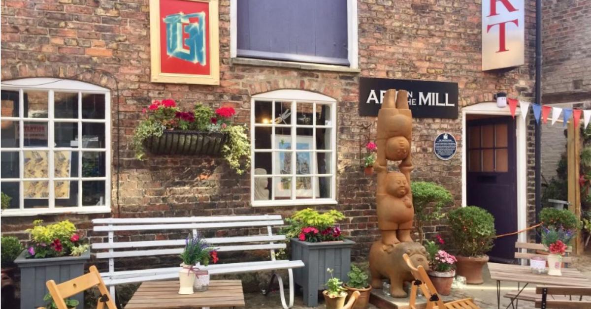 External shot of Art in the Mill, showing cafe tables and sculptures.