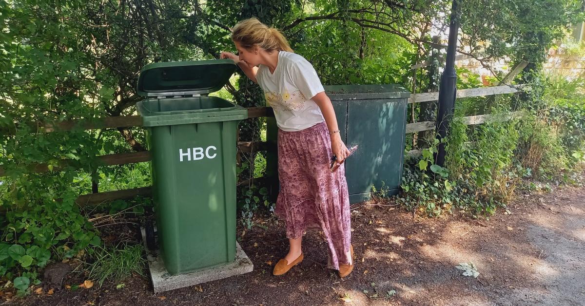Photo of Knox resident Maxie Schiffmann looking into a green wheelie bin for dog waste that North Yorkshire Council has placed near her front gate.