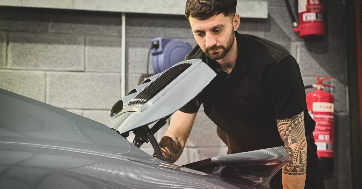 Photo of Will Mann of Flat 6 Automotive in Boroughbridge, looking into the engine of a Porsche.