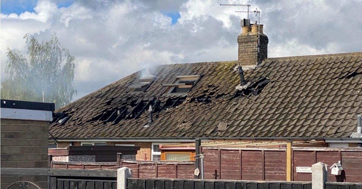 Photo of smoke billowing from a window in the fire-damaged roof of a house in Starbeck.