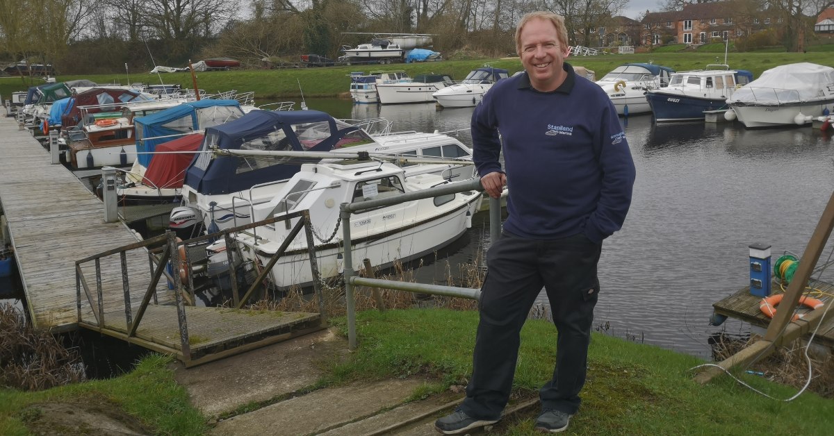Photo of Simon Taylor, owner of Boroughbridge Marina standing by a jetty with moored boats in the background.